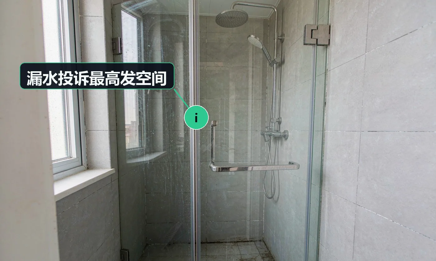 成品住宅卫生间的淋浴区:无框玻璃淋浴隔断、灰色墙砖与地漏,是家庭漏水投诉最高发的部位。